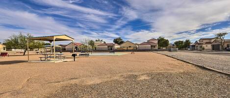 A playground with picnic tables and a covered area, surrounded by houses.