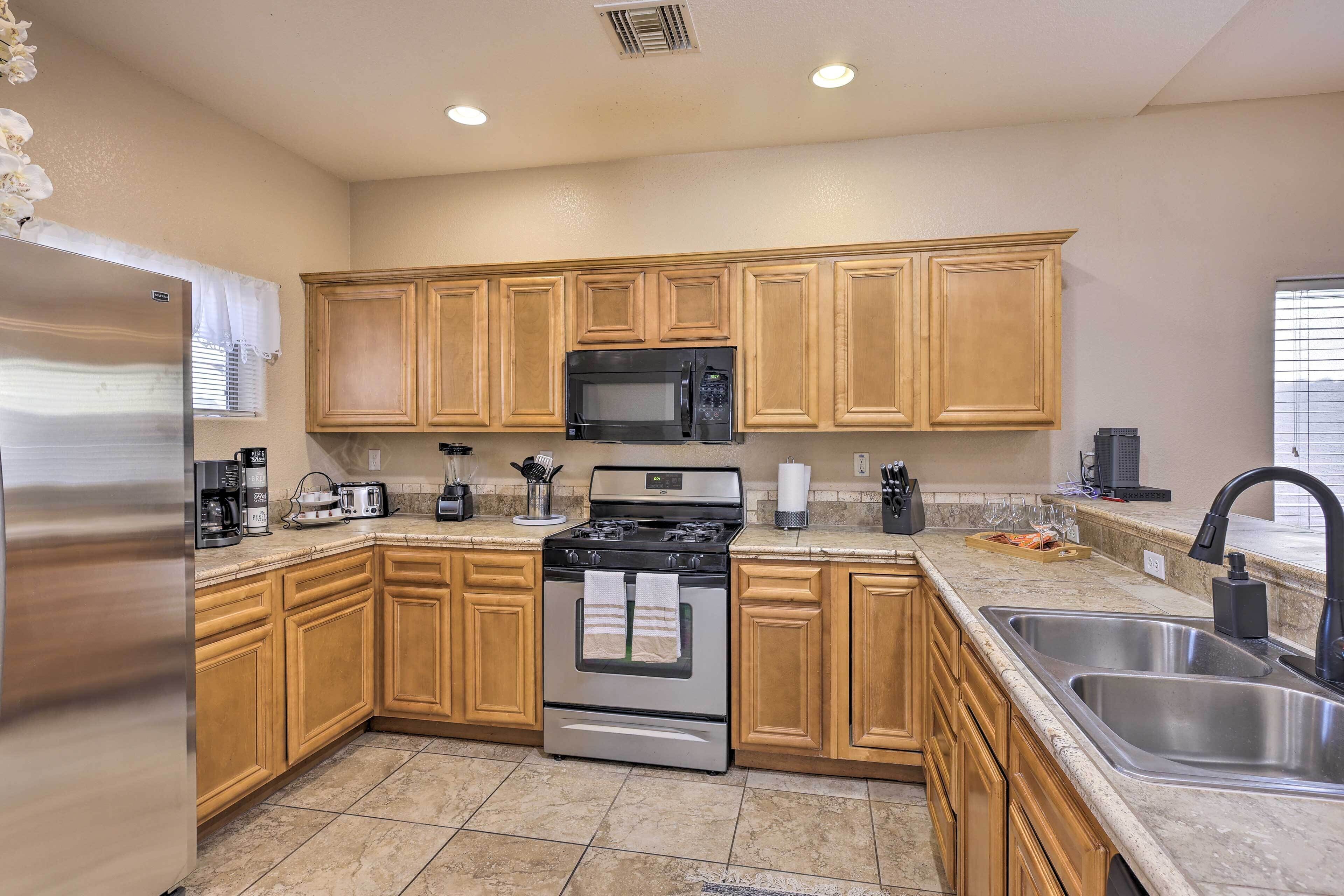A modern kitchen with wooden cabinets, stainless steel appliances, and a granite countertop.
