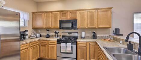 A modern kitchen with wooden cabinets, stainless steel appliances, and a granite countertop.