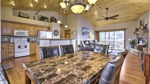 Une cuisine spacieuse dotée de meubles en bois, d’un grand îlot en granit et d’un coin repas avec des chaises en cuir.