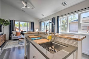 A modern kitchen with a built-in sink, wooden countertop, and a window with curtains.
