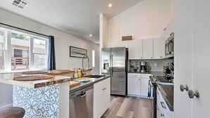 A modern kitchen with white cabinets, stainless steel appliances, a wooden countertop, and a dishwasher. - Modern Midtown Haven w/ Garage: Mt Rose Day Trips! (Reno)