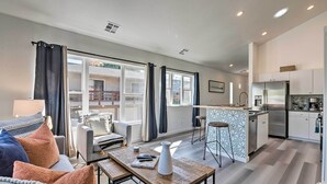 A modern living room with a sofa, coffee table, and a view of the kitchen. - Modern Midtown Haven w/ Garage: Mt Rose Day Trips! (Reno)