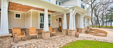 A two-story house with a covered porch, stone pillars, and a gravel pathway leading to the entrance.