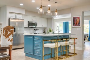 A modern kitchen with a central island, bar stools, stainless steel appliances, and pendant lighting. - Pool, Hot Tub: Family-friendly Scottsdale Home! (Scottsdale)