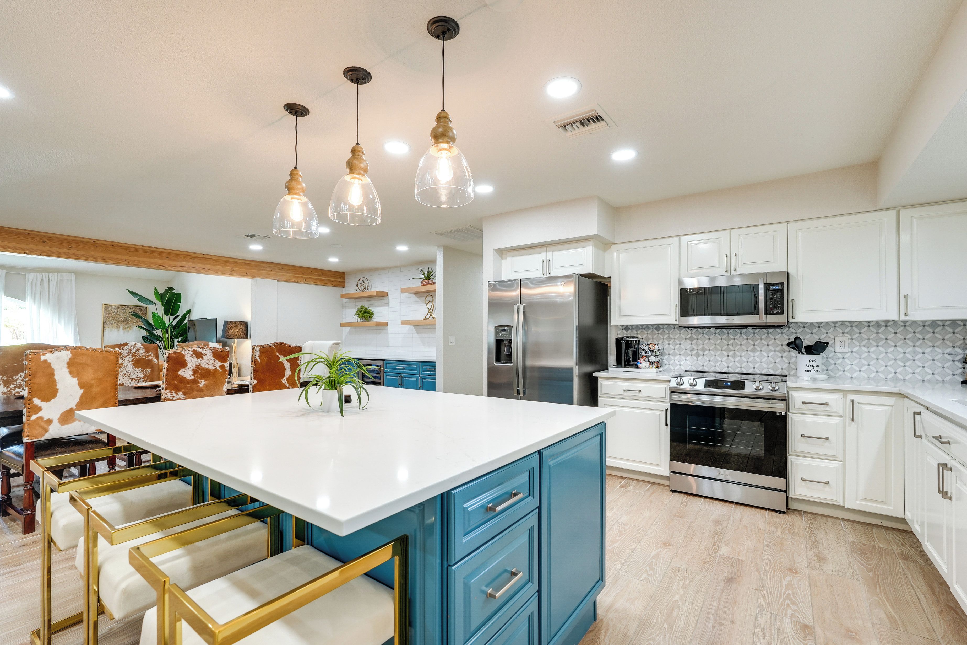 A modern kitchen with white cabinets, stainless steel appliances, and a central island with bar stools.