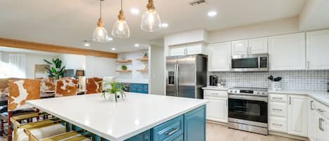 A modern kitchen with white cabinets, stainless steel appliances, and a central island with bar stools.