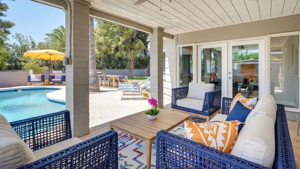 A covered outdoor area with a pool, wicker furniture, and a ceiling fan. - Pool, Hot Tub: Family-friendly Scottsdale Home! (Scottsdale)