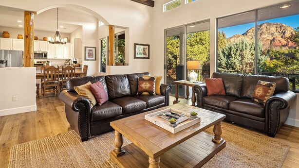A spacious living room with leather sofas, a wooden coffee table, and large windows offering mountain views. - Luxury Sedona Living: Remodeled w/ Red Rock Views! (Sedona)