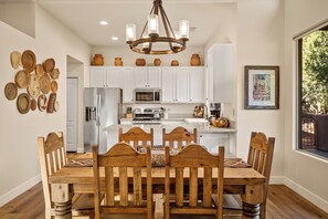 A dining area with a wooden table and chairs, white cabinets, a chandelier, and decorative pottery. - Luxury Sedona Living: Remodeled w/ Red Rock Views! (Sedona)