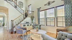 A spacious living room with a staircase, a round coffee table, and two armchairs. - Luxe Goodyear Home w/ Serene Backyard & Game Room (Goodyear)