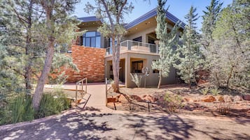 A modern two-story house with a brick facade, large windows, and a balcony.