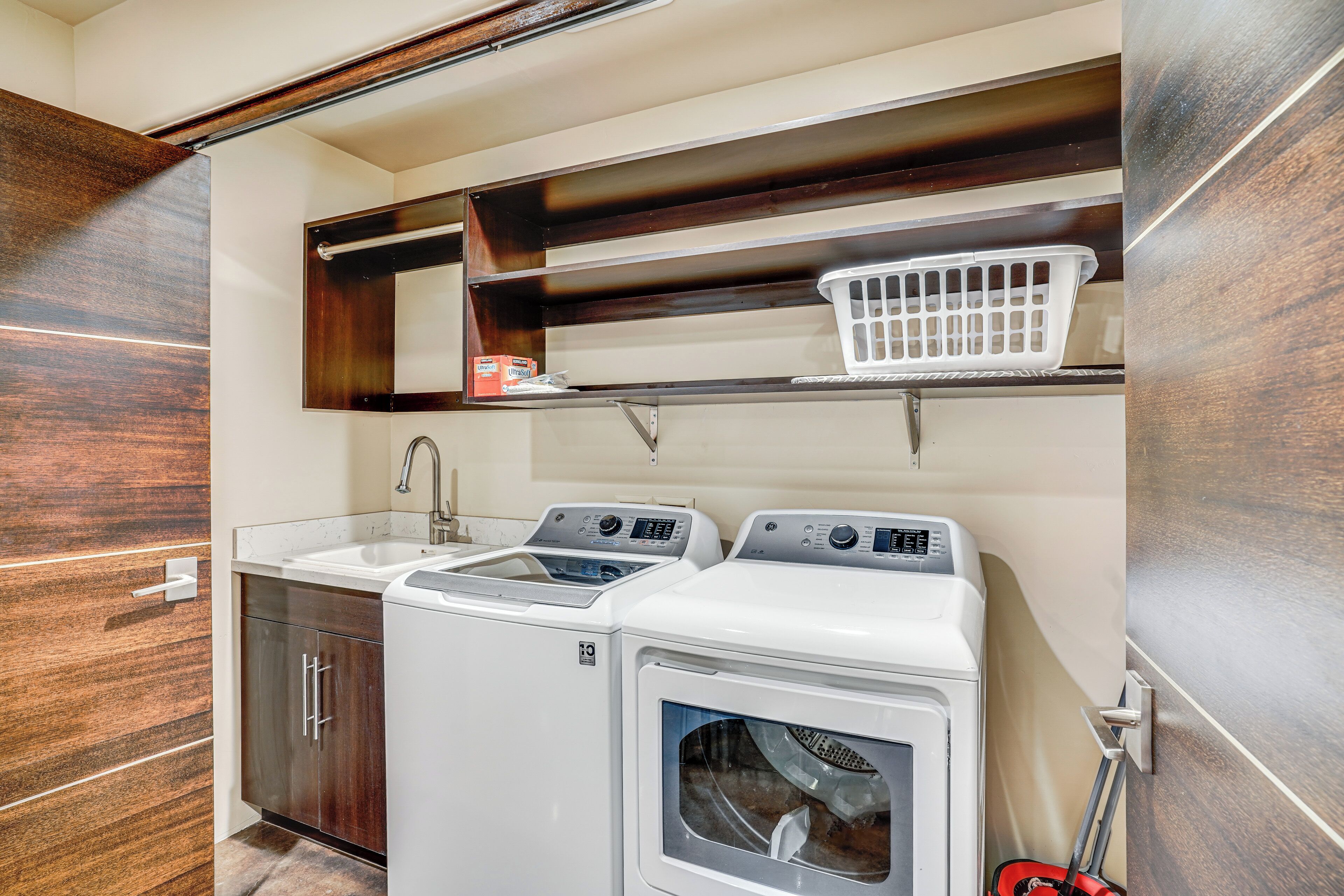 A compact laundry area with a washing machine, dryer, and sink.