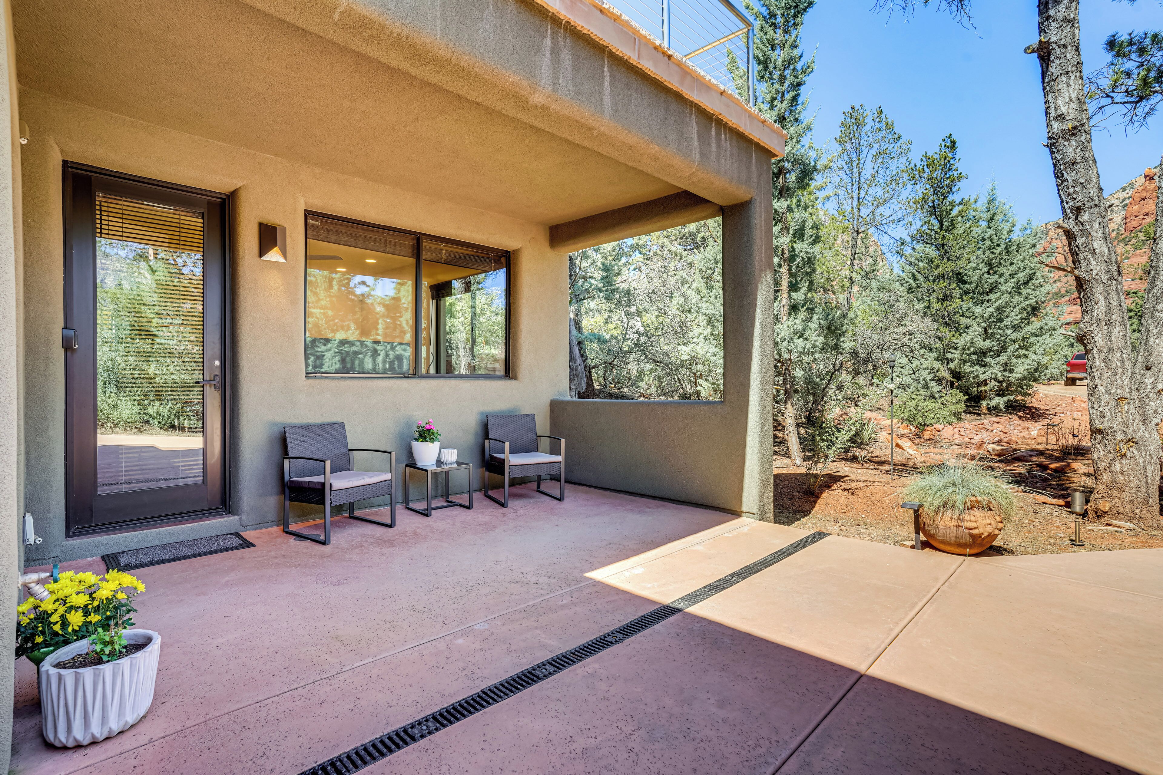 A covered patio with a seating area, a potted plant, and a view of the surrounding landscape.
