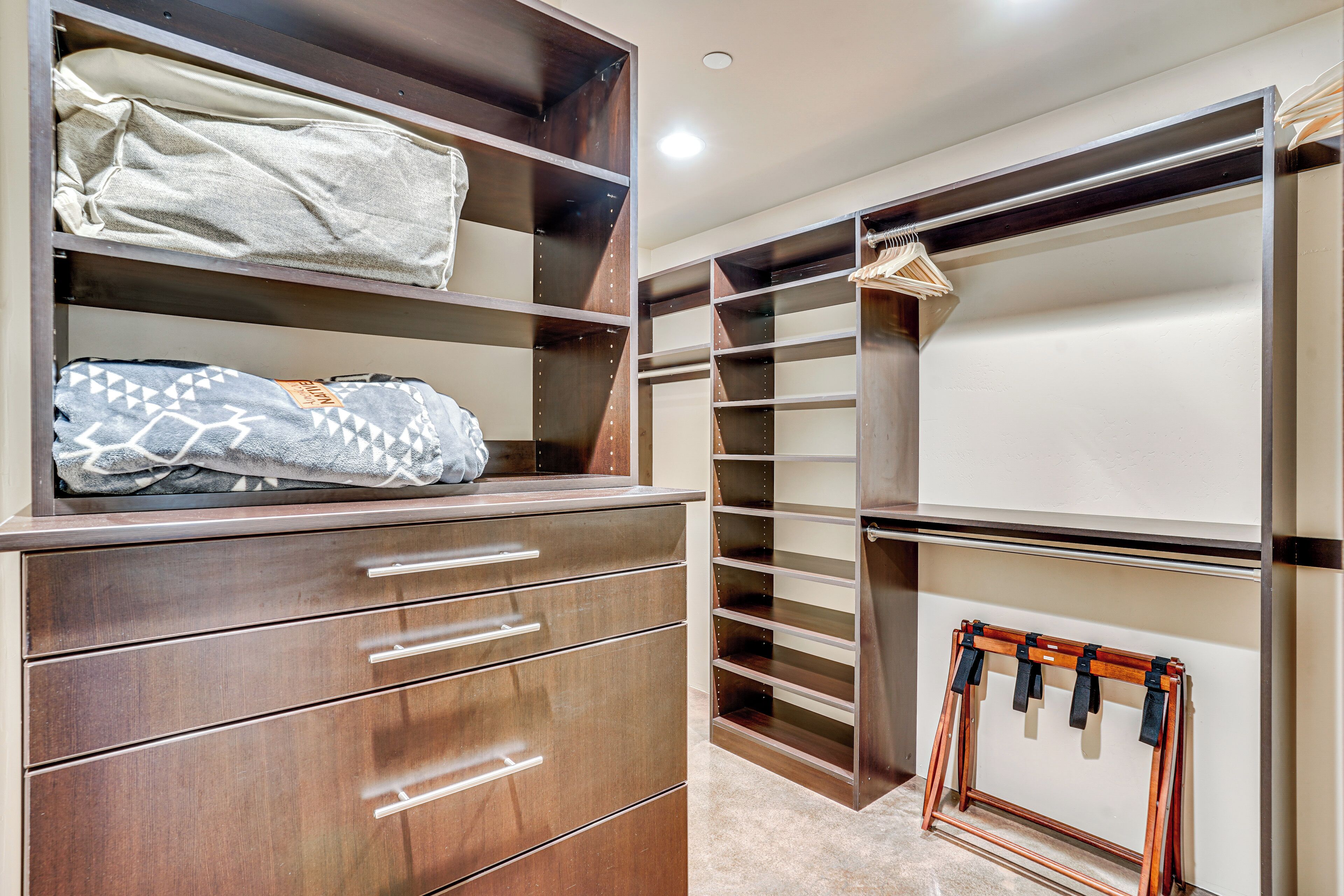 A walk-in closet with multiple shelves, drawers, and hanging space.
