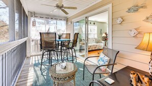 A covered patio with a table and chairs, a ceiling fan, and a view into an adjacent room. - Marina & Beach Club Access: Condo in Southport (St. James)