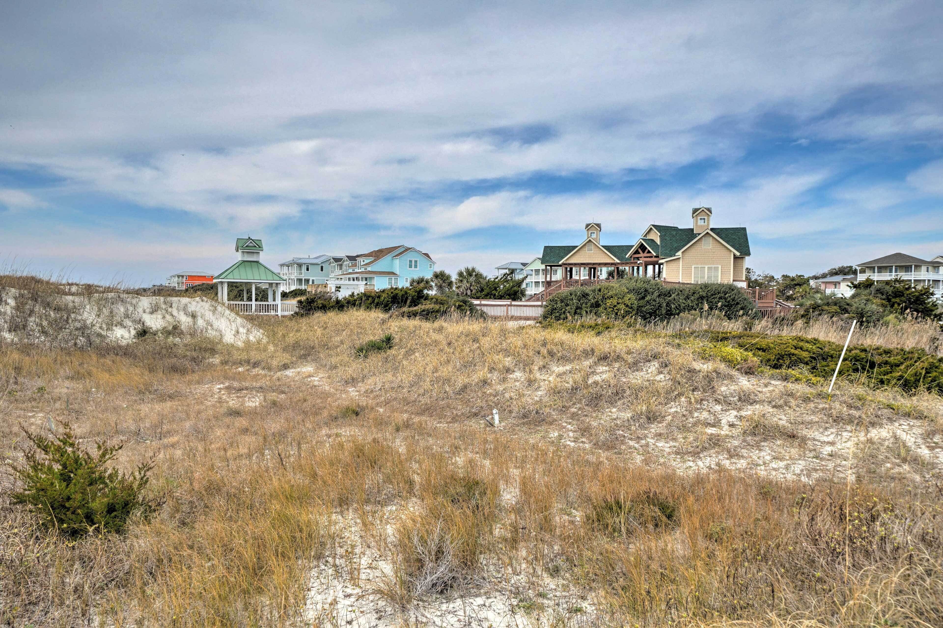 Une propriété située sur la côte, comprenant plusieurs maisons, un belvédère et une plage de sable.