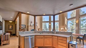 A modern kitchen with wooden cabinets, a built-in dishwasher, and large windows offering a view of trees. - Spacious Angel Fire Home w/ Deck & Resort Perks! (Angel Fire)