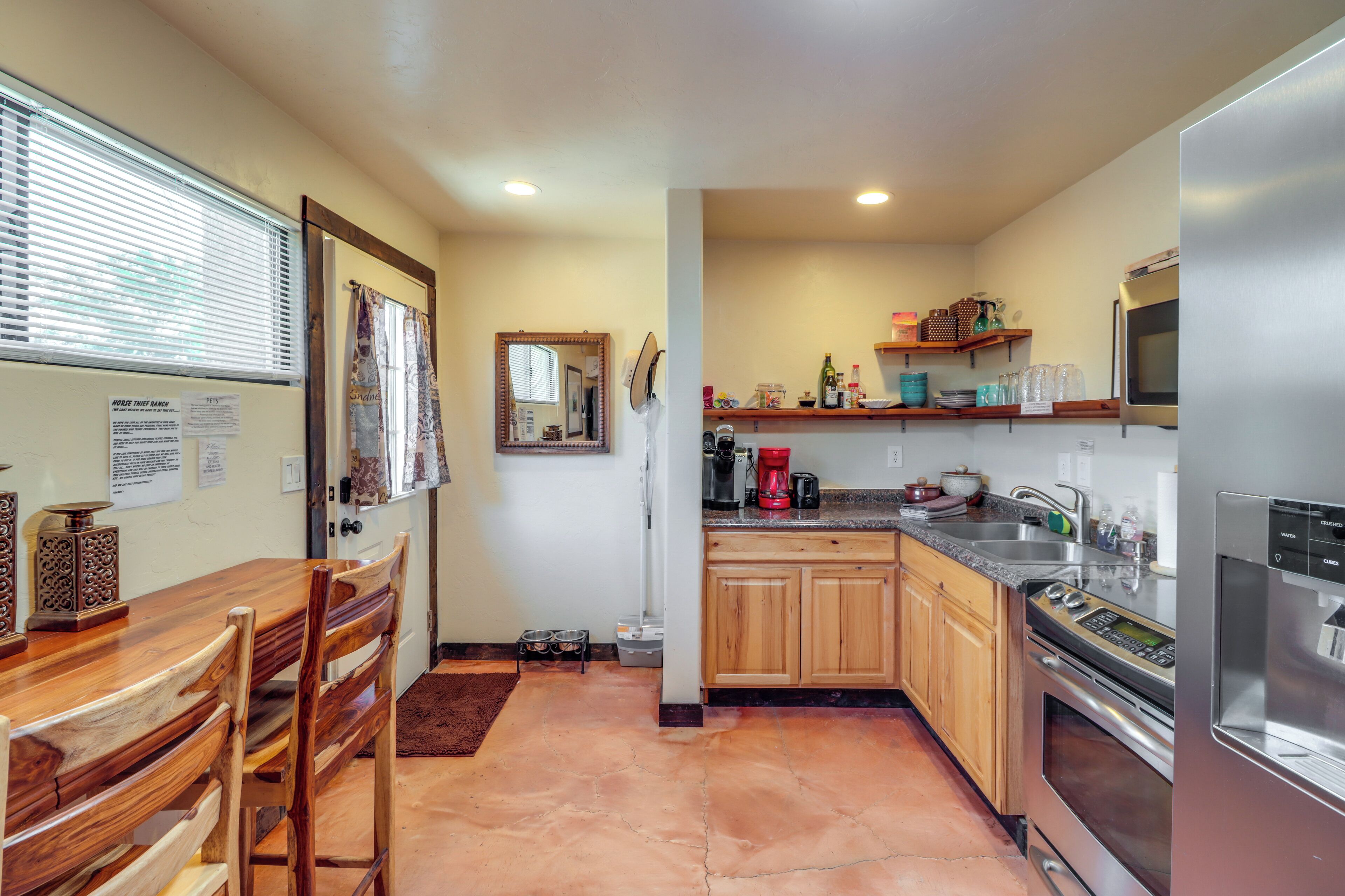 A compact kitchen with wooden cabinets, a stainless steel refrigerator, and a dining area with a wooden table and chairs.