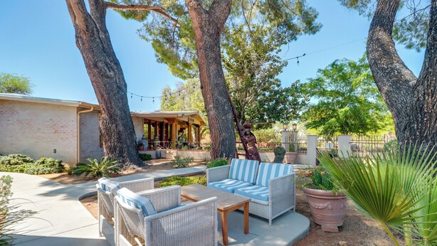 Un patio al aire libre con mobiliario de mimbre, una mesa de piedra y una planta en maceta.