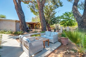 An outdoor patio area with wicker furniture, a stone table, and a potted plant. - Pet-friendly Tucson Casita: Shared Swim Spa! (Tucson)