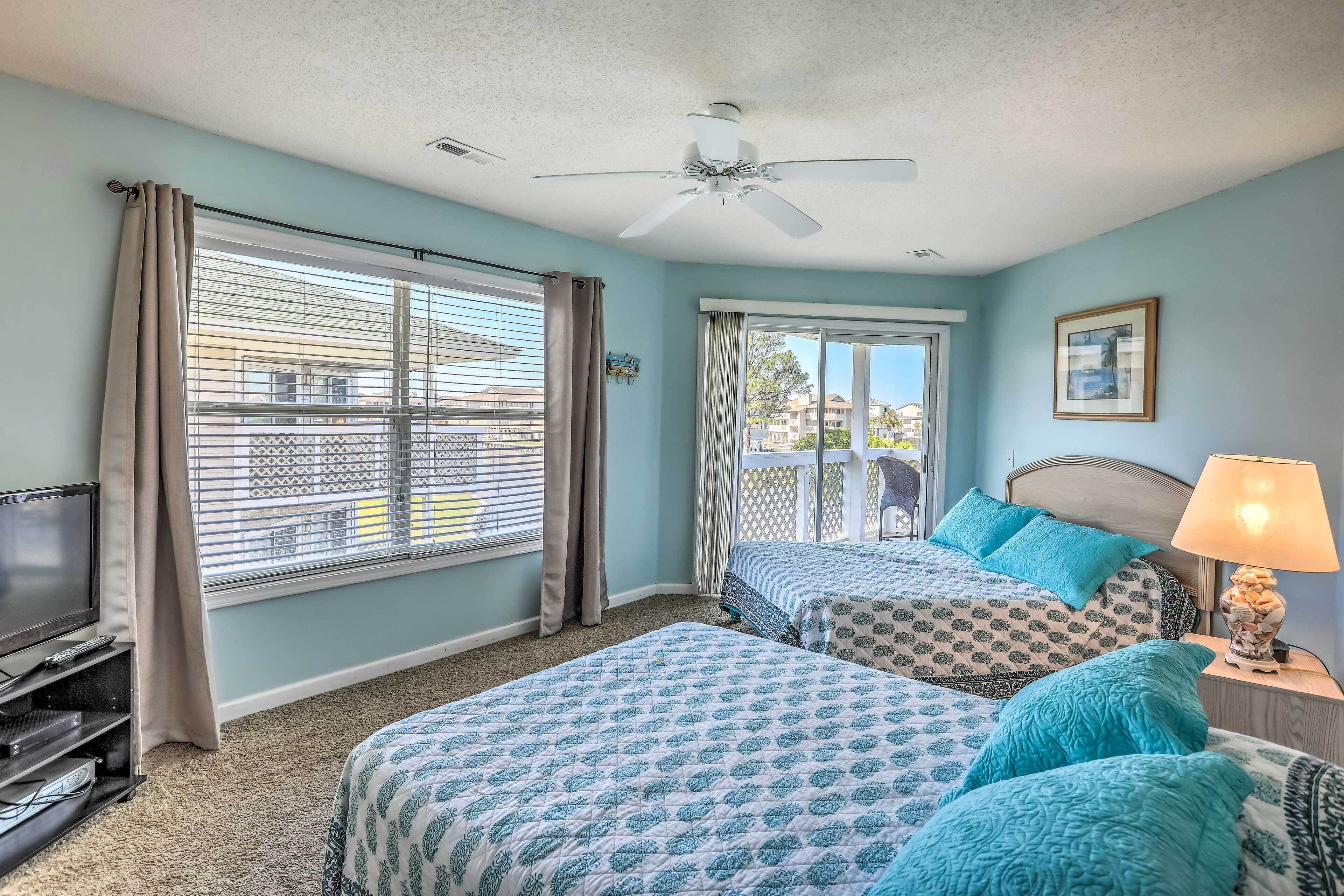 A bedroom with two beds, a ceiling fan, a TV, and a window with curtains.