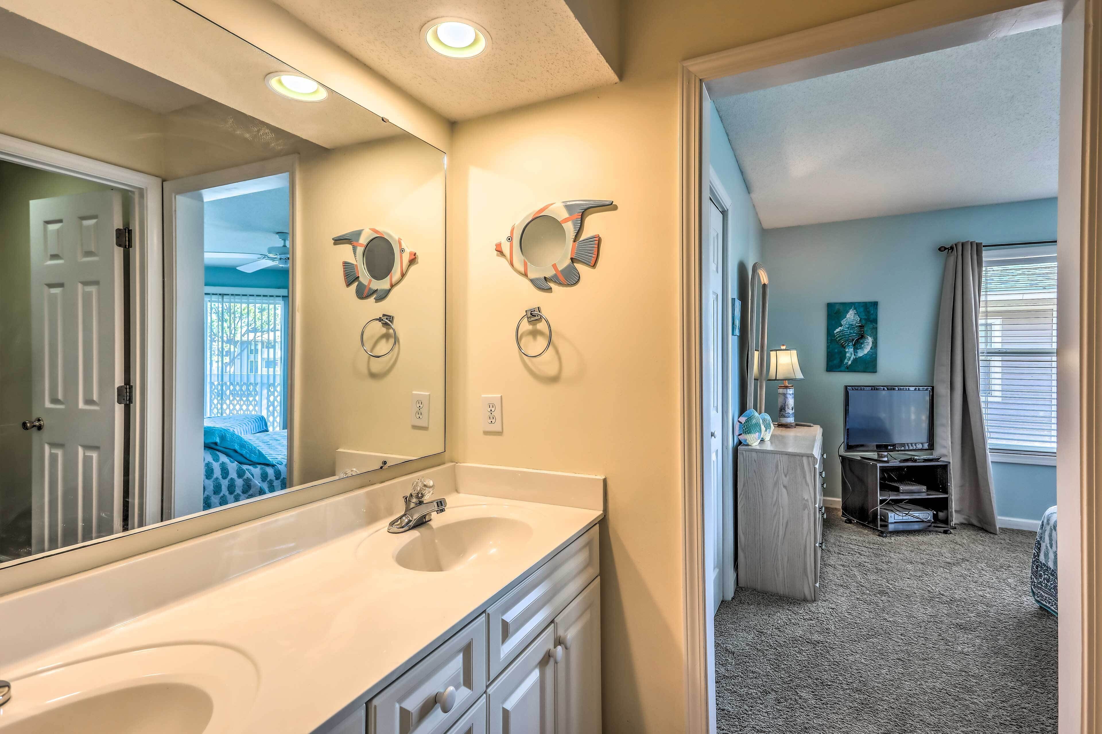 A bathroom with a large mirror, two towel rings, a sink, and a vanity.