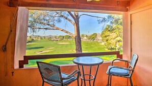 A room with a large window overlooking a golf course, a ceiling fan, and two wicker chairs. - Resort Perks, Course Views: Paradise Valley Condo! (Phoenix)