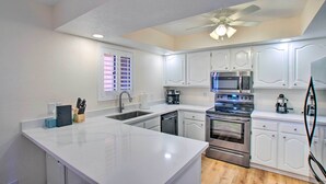 A modern kitchen with white cabinetry, a central island, stainless steel appliances, and a ceiling fan. - Resort Perks, Course Views: Paradise Valley Condo! (Phoenix)