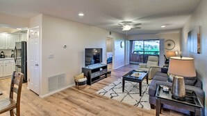 A modern living room with a TV, sofa, and coffee table. There is a kitchen area with cabinets and a refrigerator. - Resort Perks, Course Views: Paradise Valley Condo! (Phoenix)