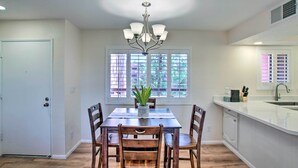 A dining area with a table, chairs, a chandelier, and a window with blinds. - Resort Perks, Course Views: Paradise Valley Condo! (Phoenix)