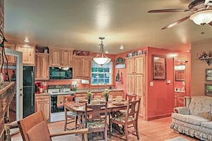 A kitchen with wooden cabinets, a dining table with chairs, and a ceiling fan.
