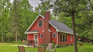 A red house with a chimney, surrounded by a well-maintained lawn and trees. - Secluded Birnamwood Cottage w/ Deck & River Views! (Birnamwood)