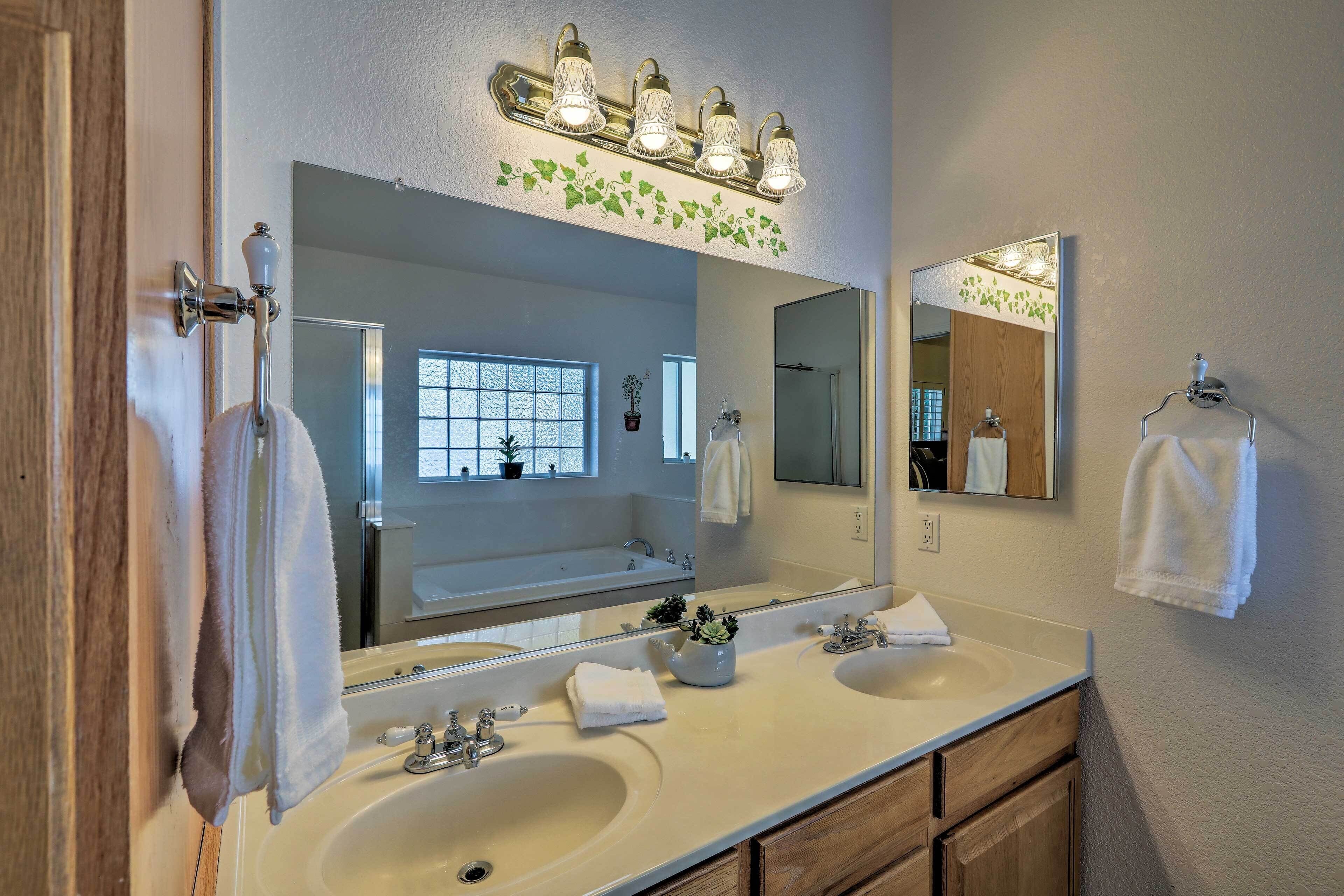 A bathroom with two sinks, a large mirror, and a vanity with wooden cabinets.