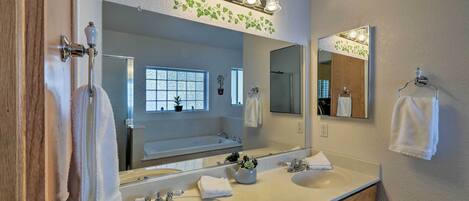 A bathroom with two sinks, a large mirror, and a vanity with wooden cabinets.