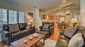 A spacious living room with leather sofas, a wooden coffee table, and a dining area in the background.