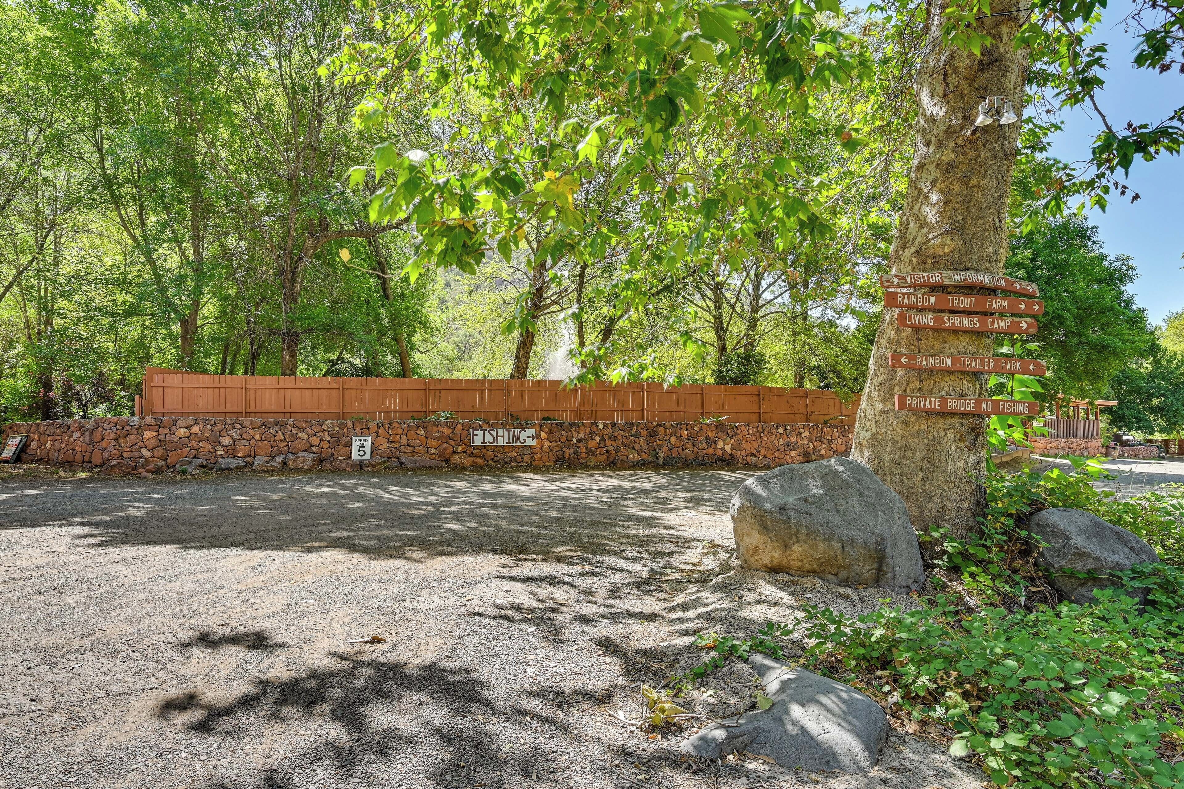 A gravel parking area with directional signs for visitor information, Rainbow Trout Farm, Living Springs Camp, and Rainbow Trailer Park.