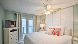 A bedroom with a large bed, a ceiling fan, a TV on a dresser, and a view of the outdoors. - Cozy Beachfront Escape w/ Pool & Gulf Access! (Gulf Shores)