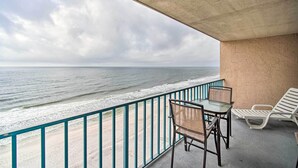 A balcony with a view of the ocean, a table, two chairs, and a railing. - Cozy Beachfront Escape w/ Pool & Gulf Access! (Gulf Shores)