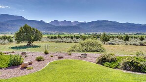 A landscaped garden with a large tree, rocks, and a view of distant mountains. - Zion Mountain Guest House w/ Canyon Vistas! (New Harmony)