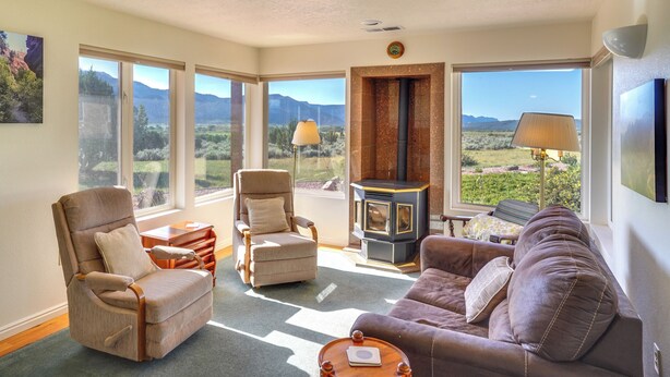 A spacious living room with large windows, a fireplace, and comfortable seating. - Zion Mountain Guest House w/ Canyon Vistas! (New Harmony)