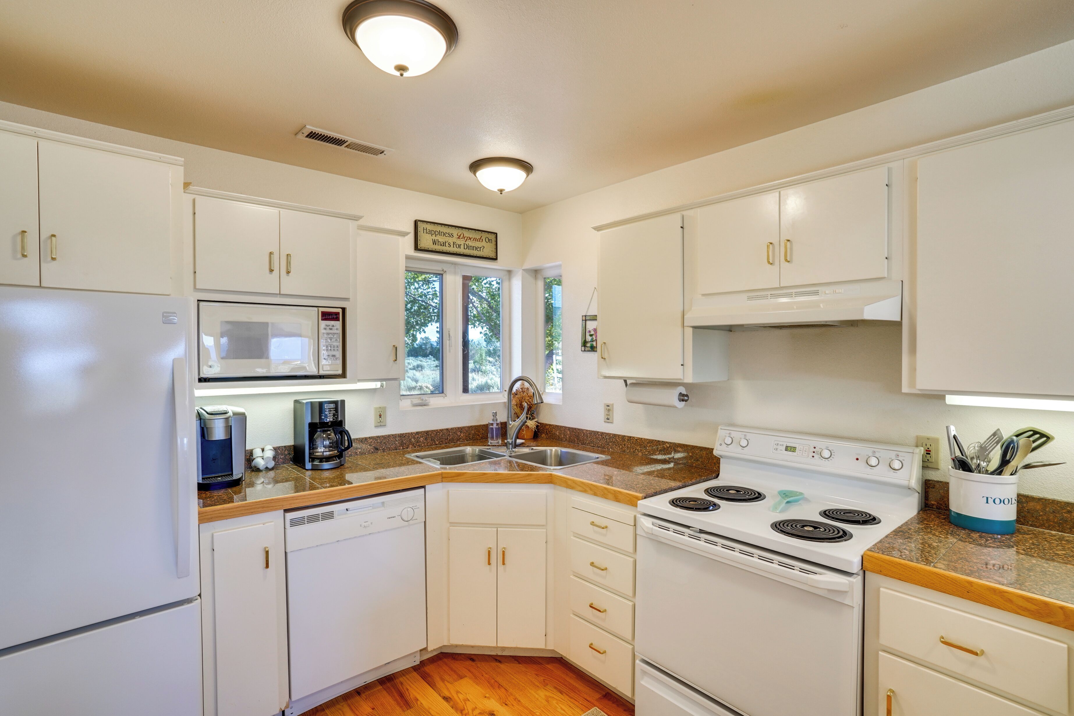 A kitchen with white cabinets, a microwave, a coffee maker, a sink, and a stove.
