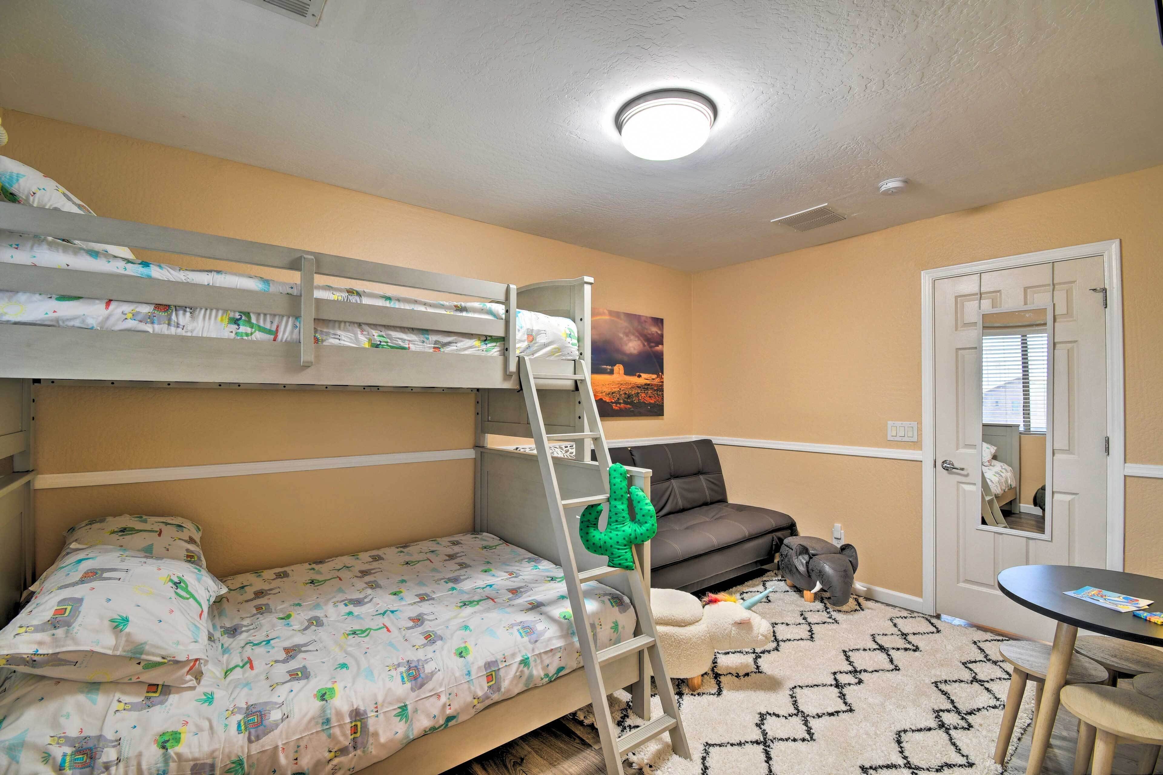 A bunk bed room with a ladder, a sofa, a small table, and a door with a mirror.
