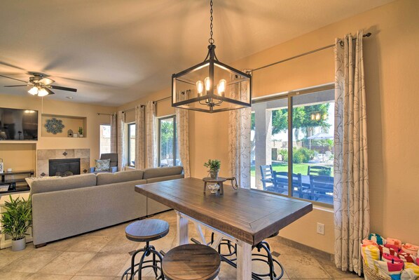 A spacious living room with a large sofa, a wooden dining table, and a ceiling fan.