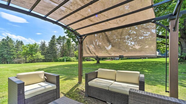 An outdoor patio area with wicker furniture and a canopy. - Stylish Suburban Home w/ Pool! 10 Mi to Royal Mtn (Johnstown)