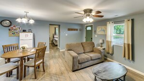 Un salon comprenant un canapé, une table à manger avec des chaises, un ventilateur de plafond et une petite table.