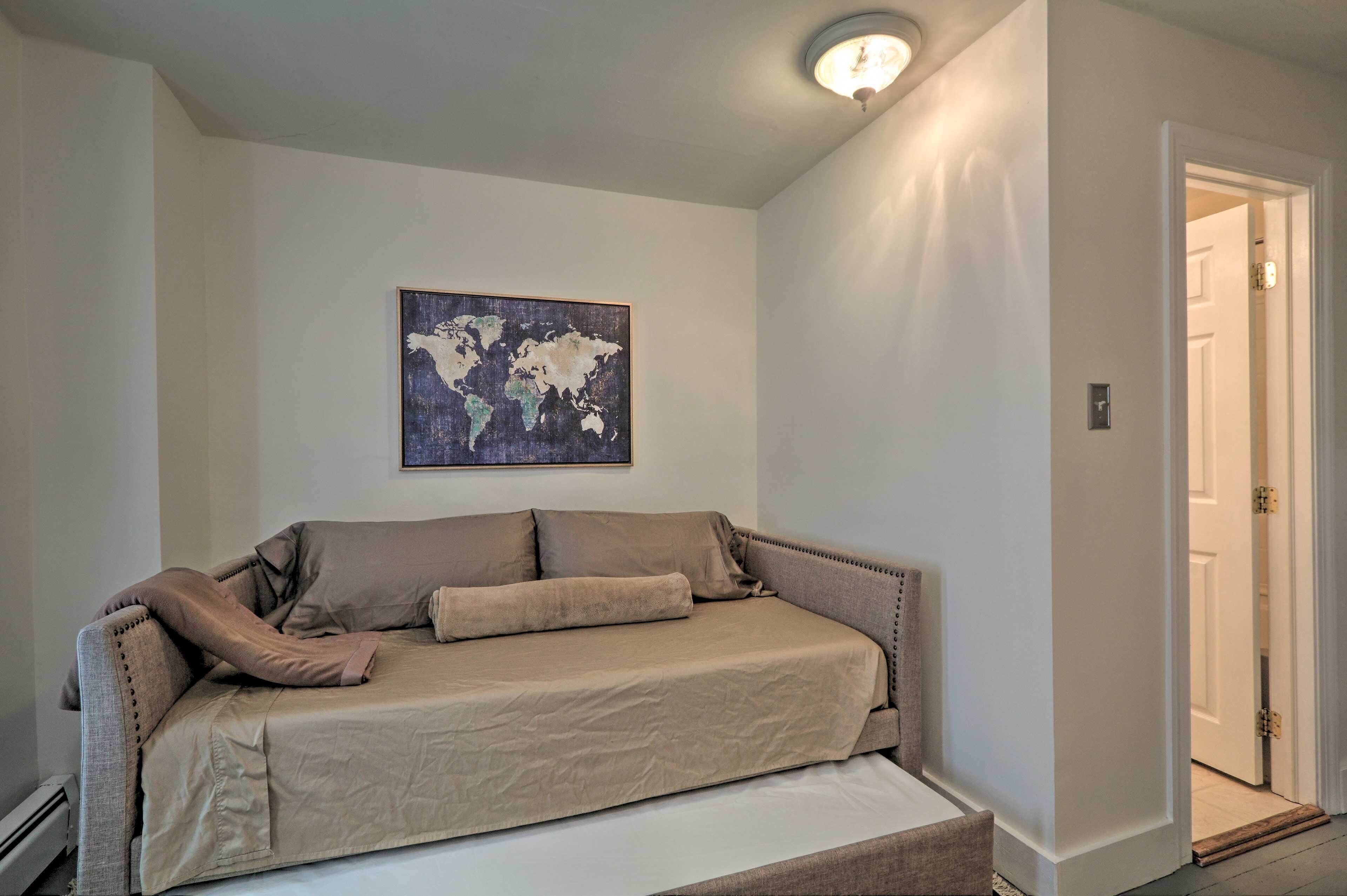 A room with a beige sofa, a world map artwork on the wall, and a door to the right.
