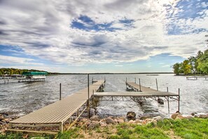 A lakeside dock with wooden walkways and a grassy foreground. - Delightful Isle Retreat w/ Boat Dock & Slip! (Isle)