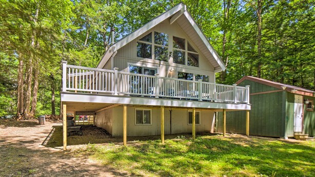 A two-story cabin with a balcony, surrounded by trees. - Cozy Maine Lakefront Escape Fall Foliage & Fire (Limerick)
