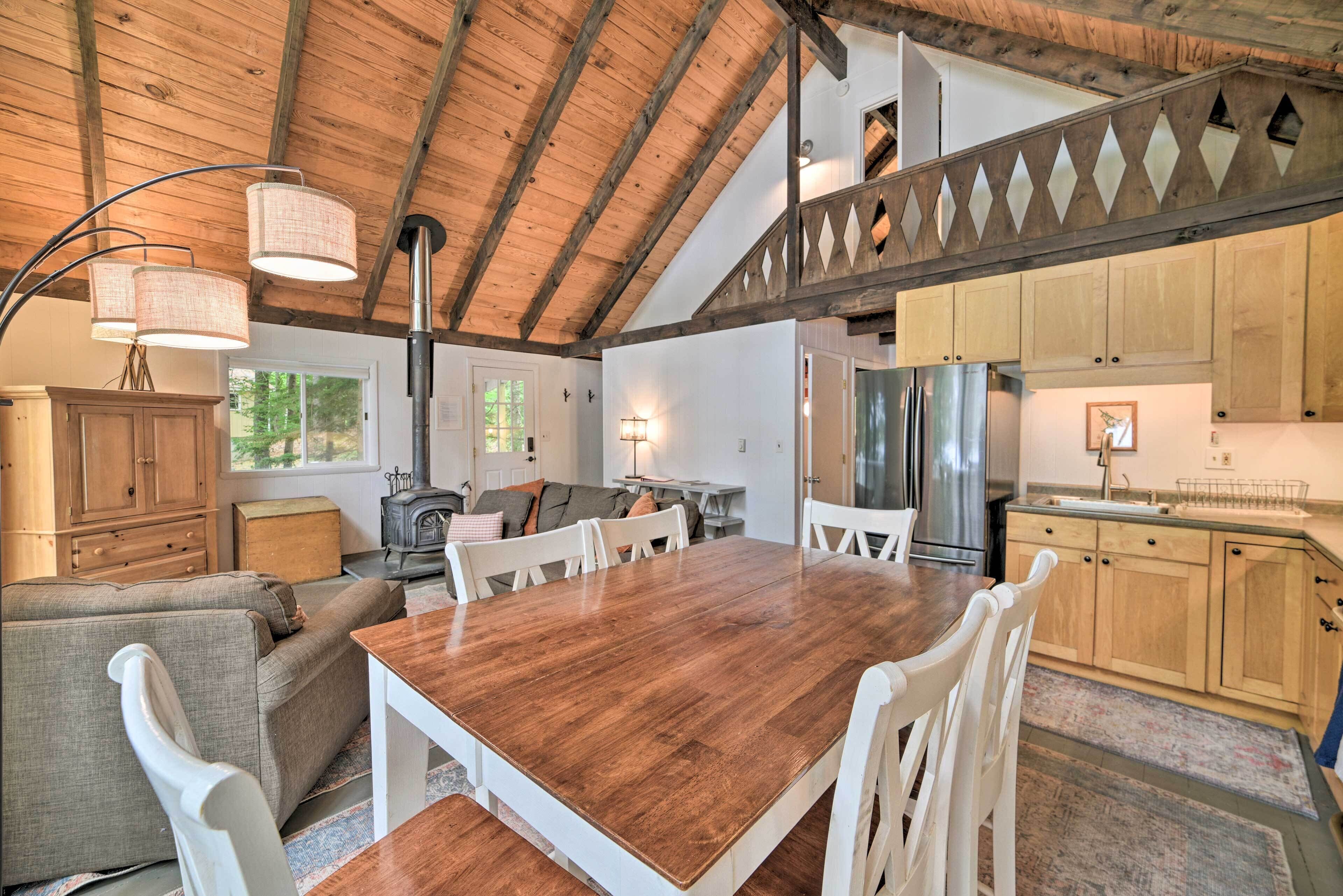 A spacious kitchen with wooden cabinets, a large dining table, and a high ceiling with exposed beams.